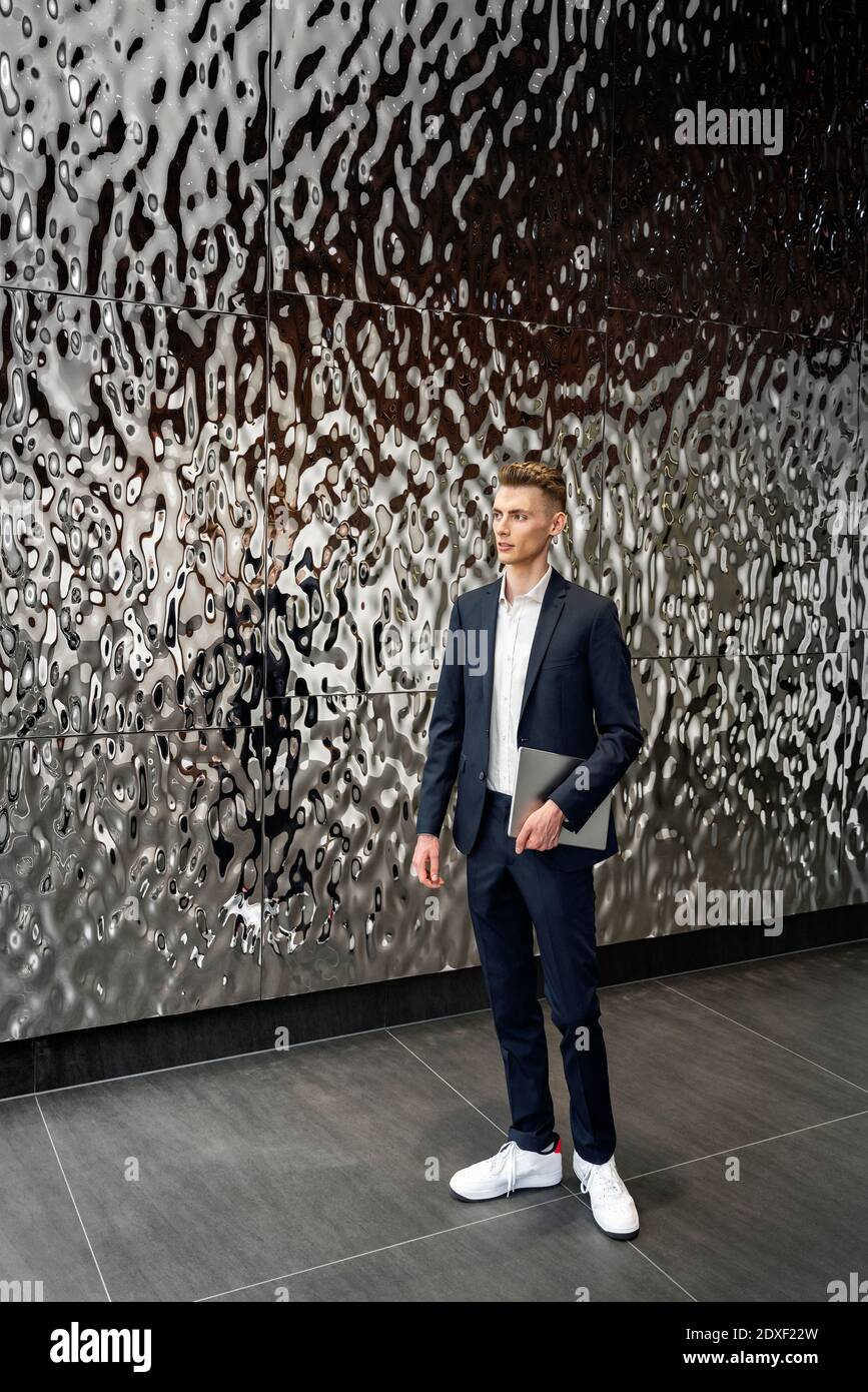Young entrepreneur holding digital tablet while standing by wall Stock Photo