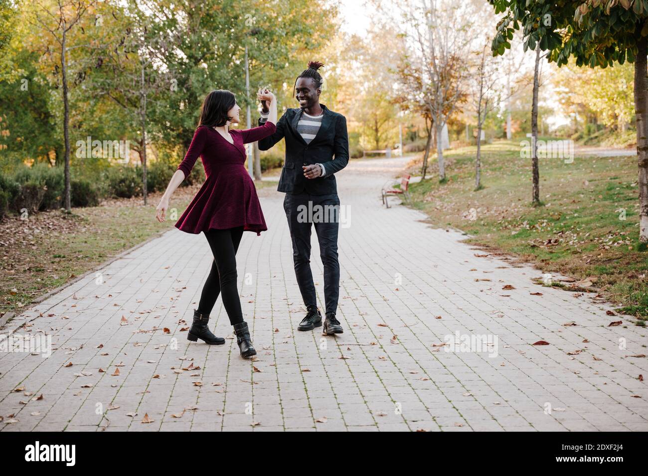 Happy multi ethnic couple dancing in park during autumn Stock Photo