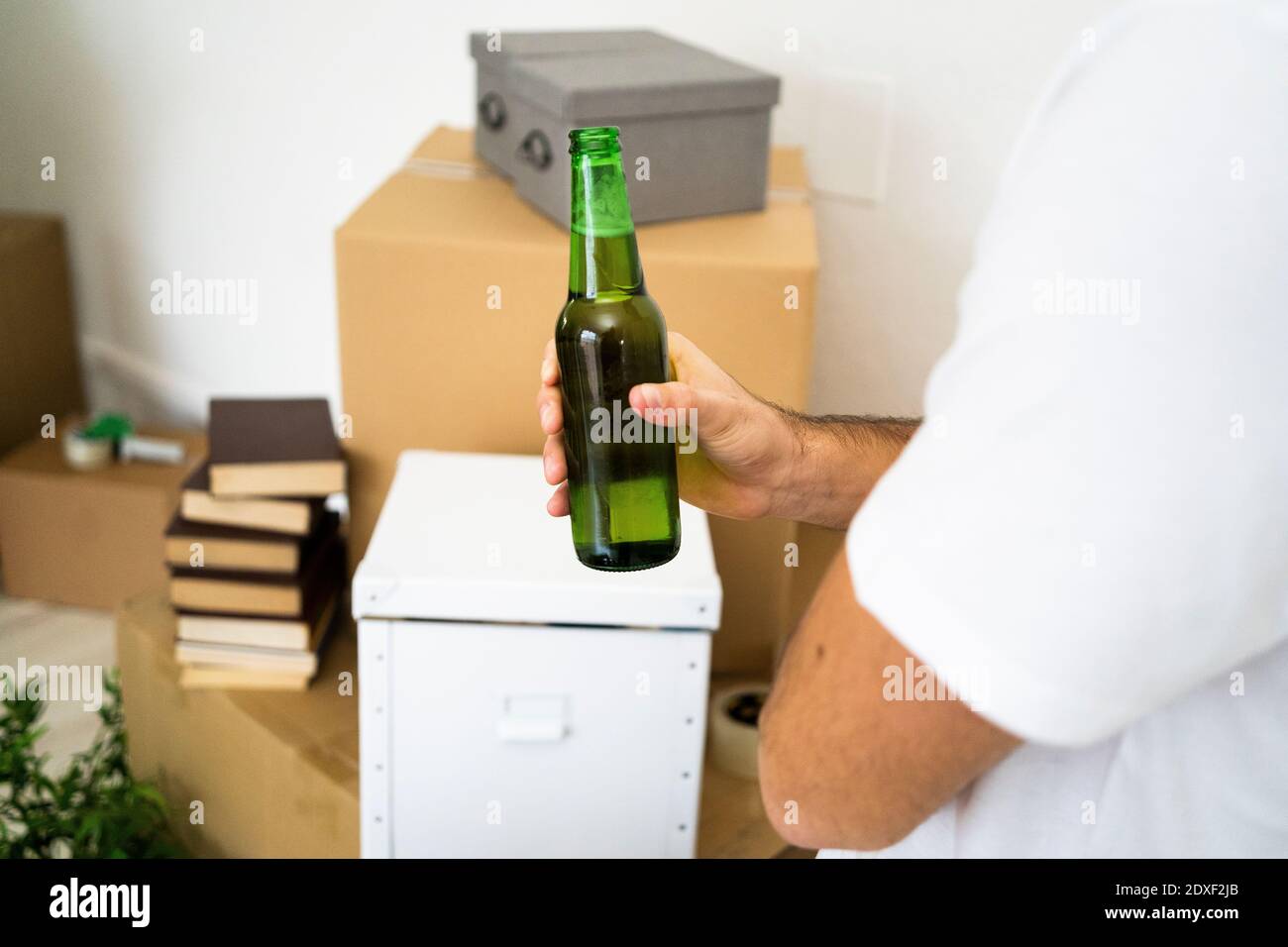 Man holding beer bottle while taking a break from moving in new