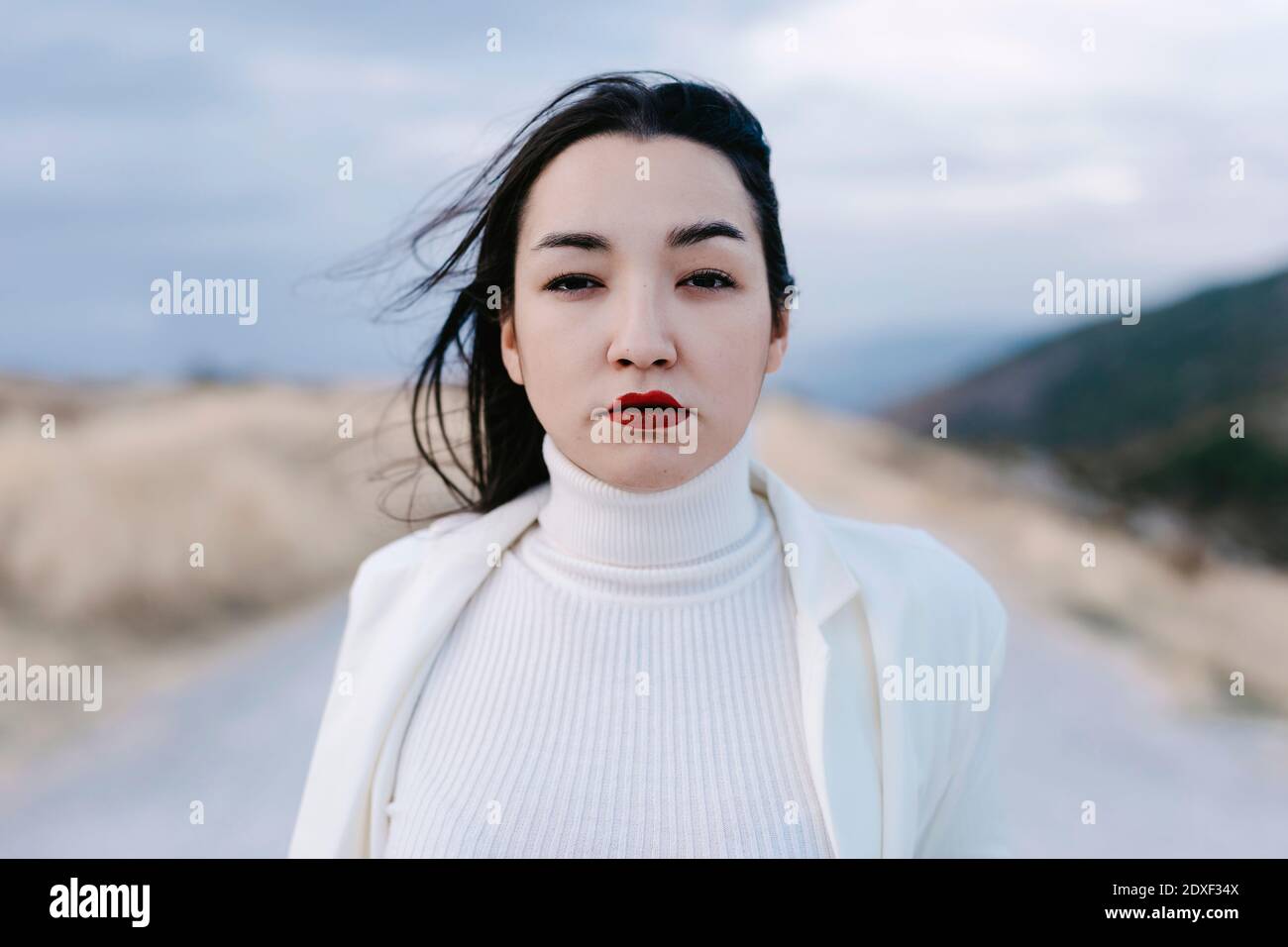 Nostalgic portrait of woman dressed in white in cloudy field at sunset