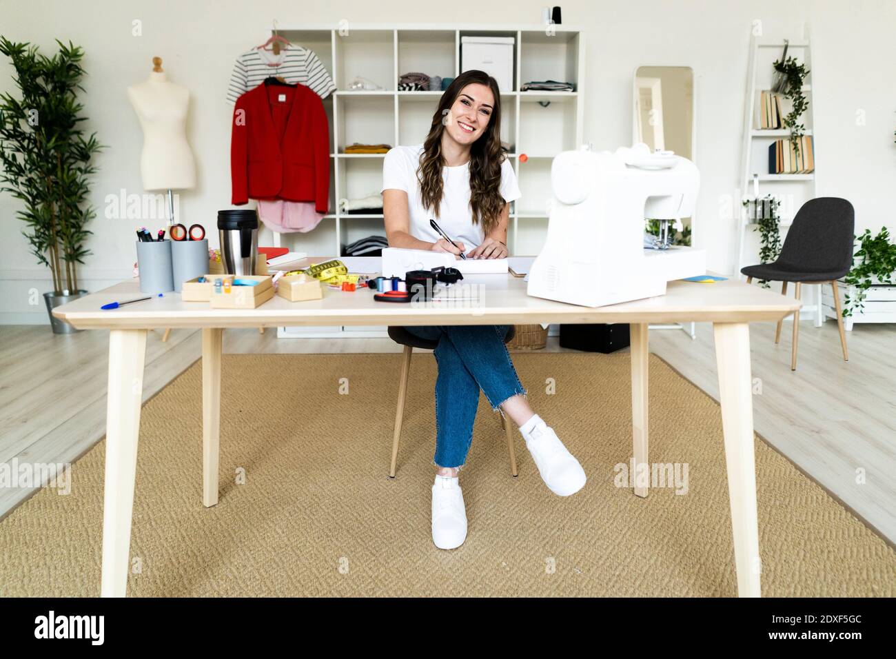 Creative female tailor smiling while sitting in studio Stock Photo