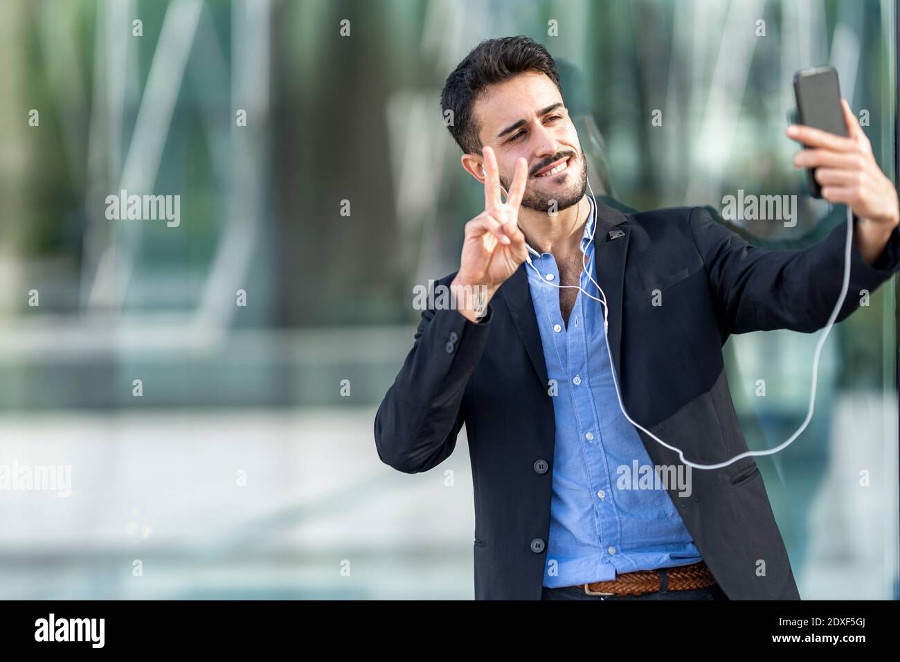 Confident businessman showing peace sign while taking selfie Stock Photo