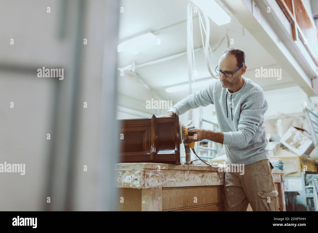 Craftsman using sander on furniture while standing at Stock