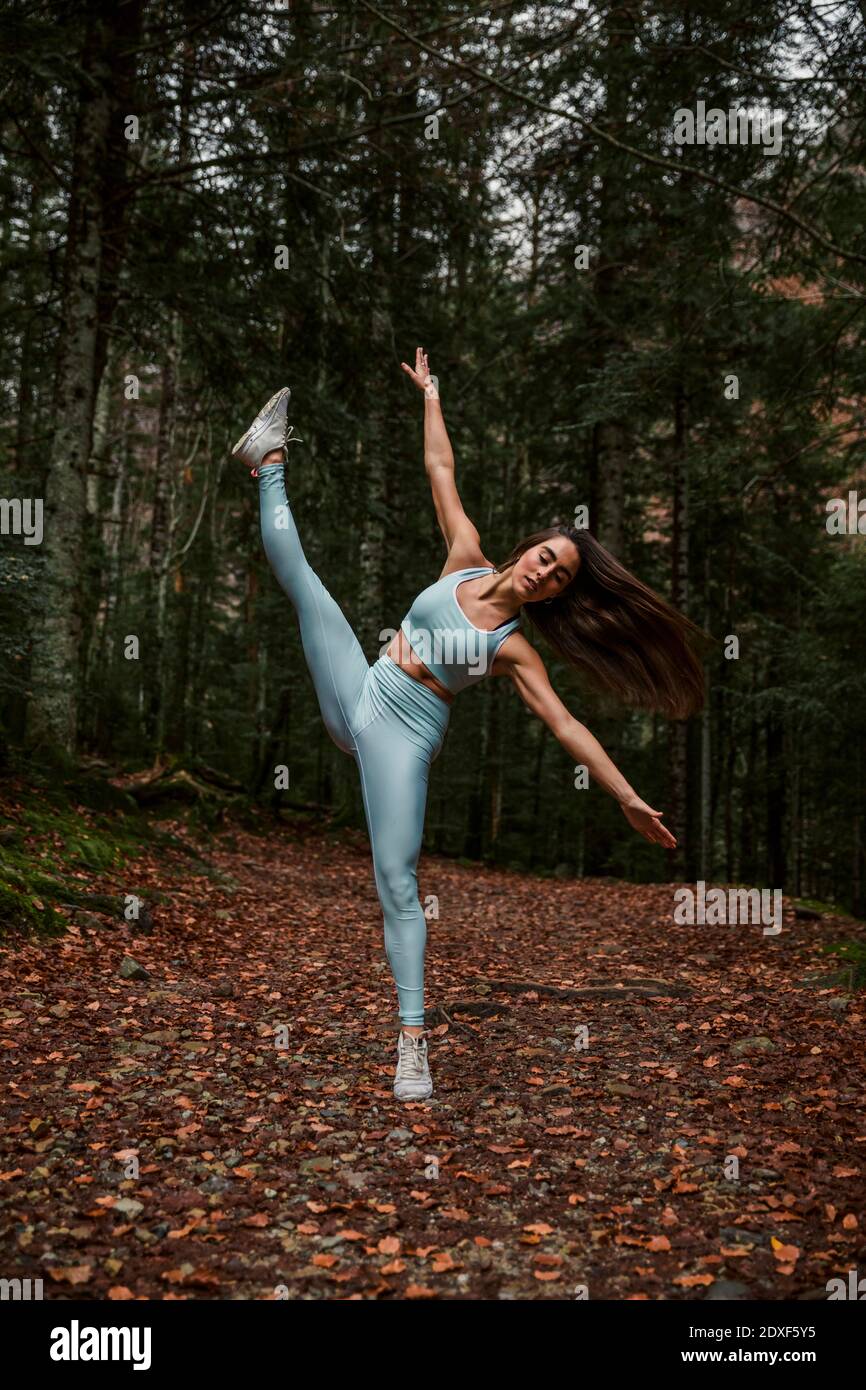 Woman with arms outstretched practicing rhythmic gymnastics in forest Stock Photo