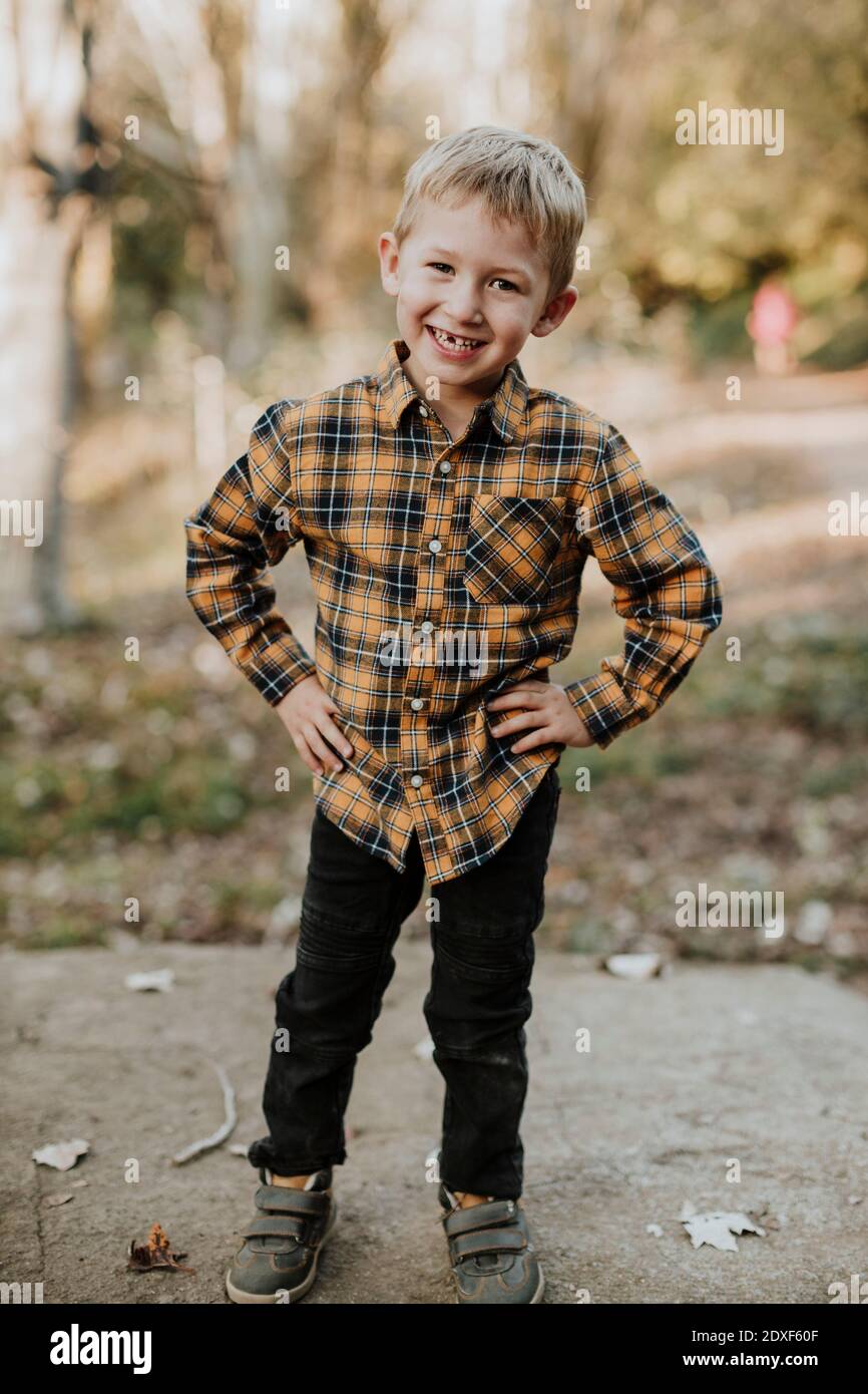Smiling boy with hand on hip standing in forest Stock Photo