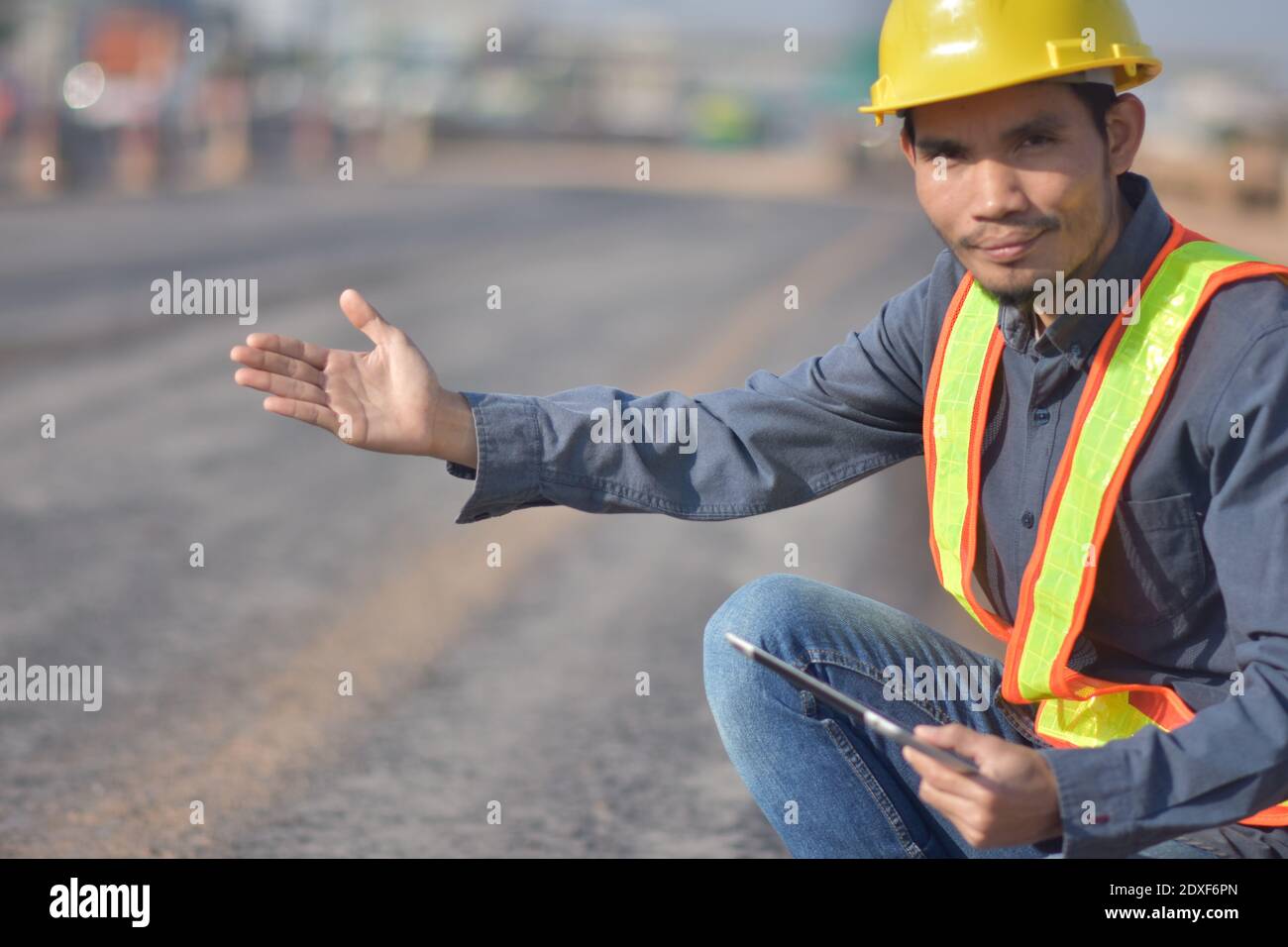 Engineering hold tablet is checking  surface of road in the road construction area. Land transportation system Stock Photo