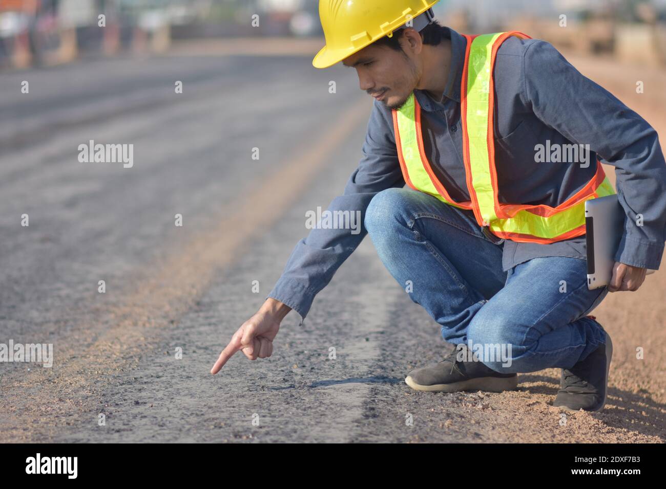 Engineering hold tablet is checking  surface of road in the road construction area. Land transportation system Stock Photo