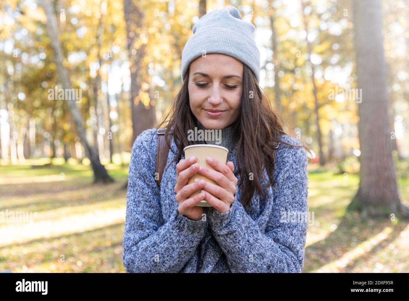 Female hiker holding tea cup in Cannock Chase woodland during winter Stock Photo