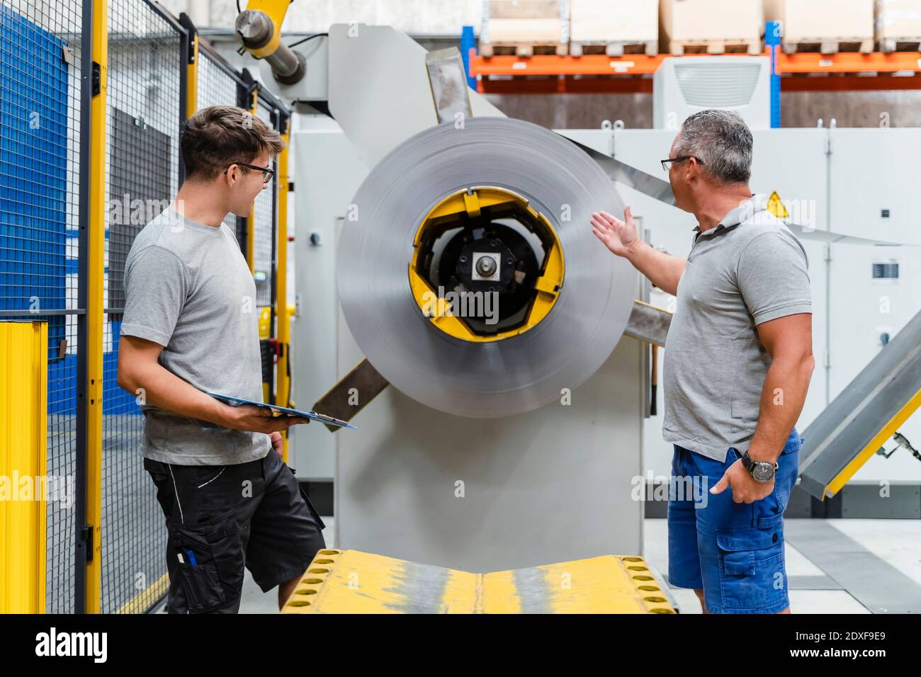 Male colleagues testing machinery in illuminated industry Stock Photo ...
