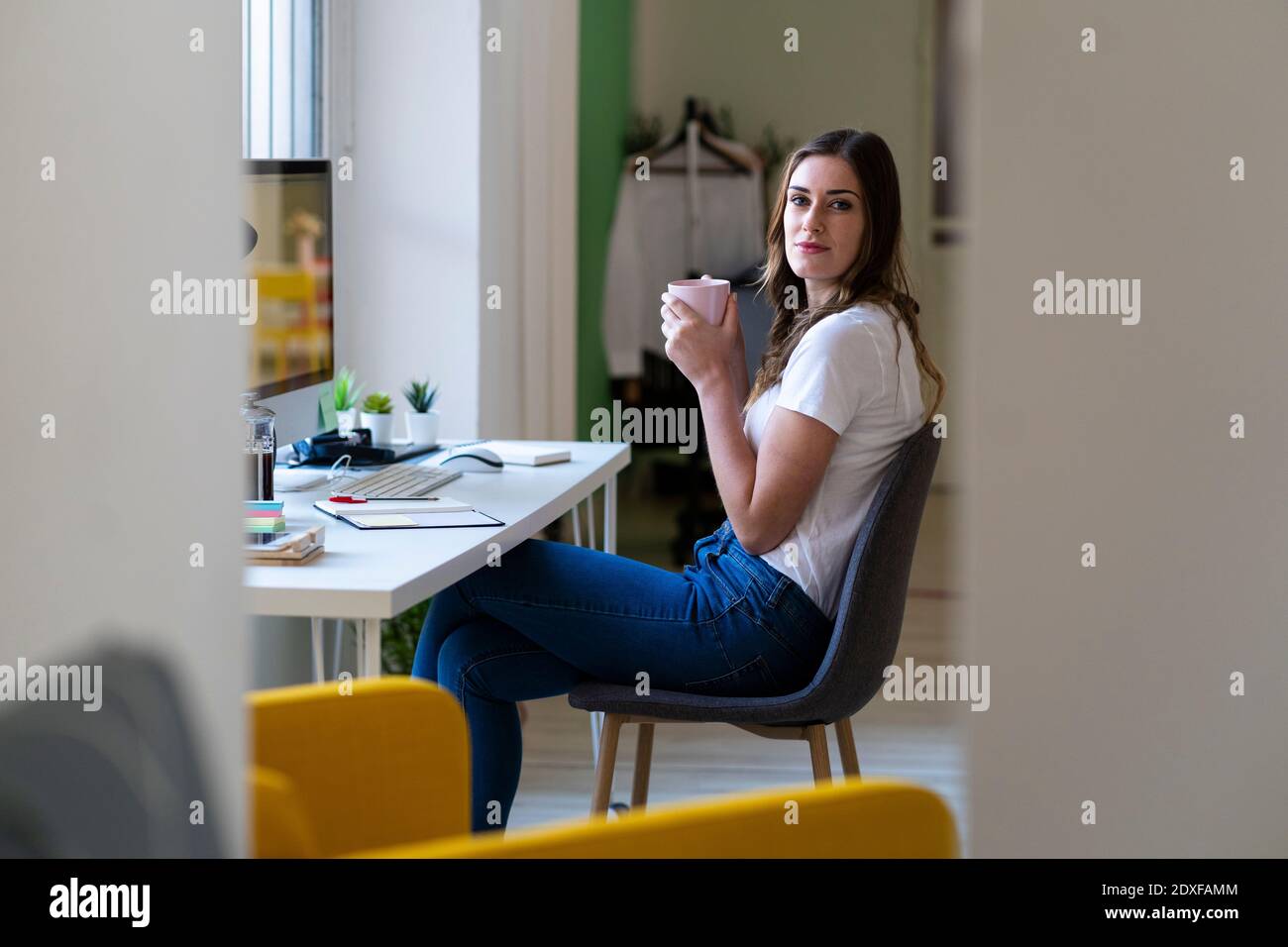 Businesswoman holding coffee cup while sitting on chair at office Stock Photo