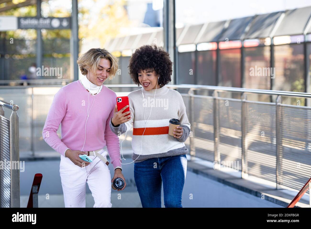Young multi-ethnic friends sharing mobile phone at railroad station Stock Photo