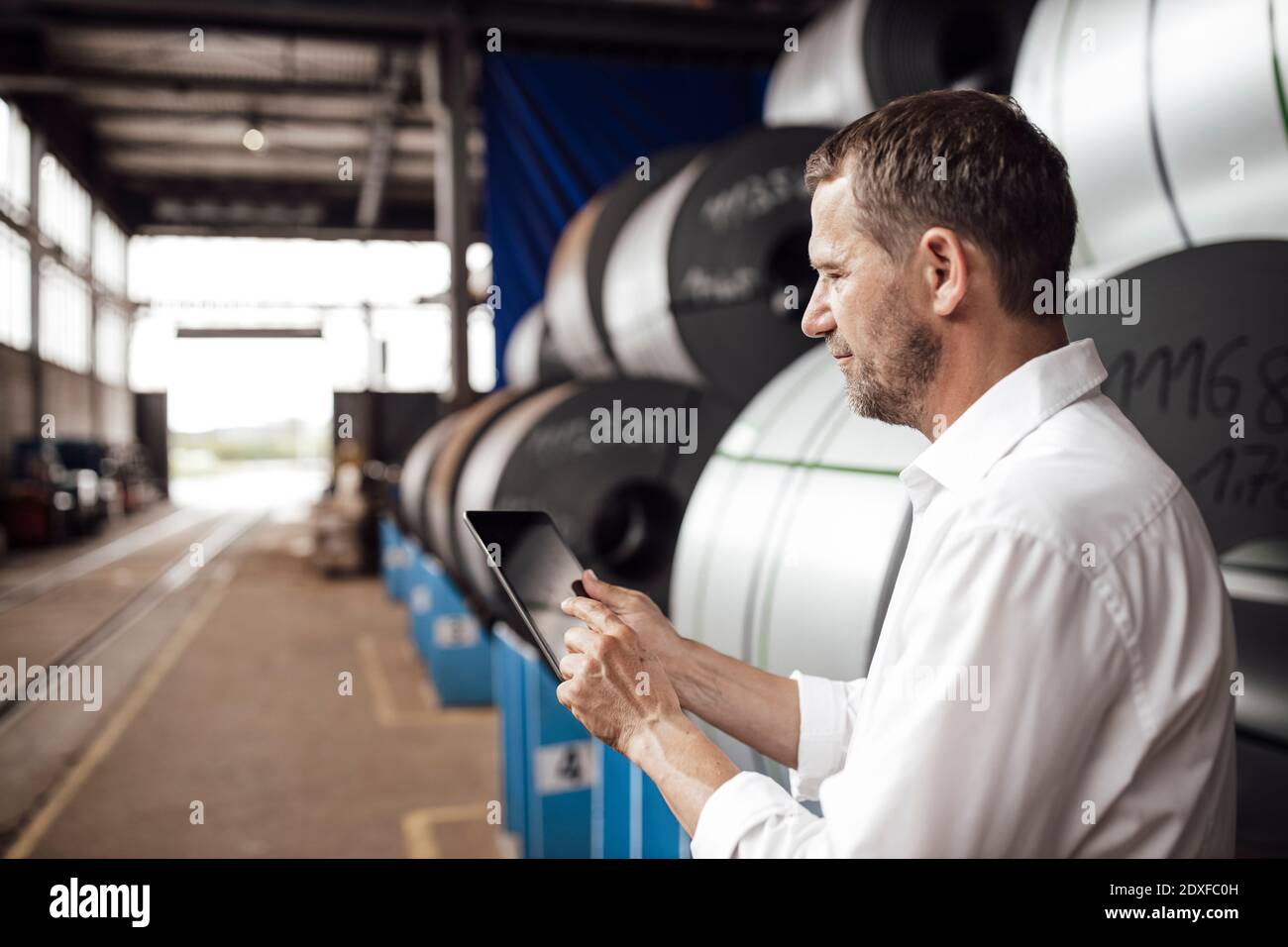 Male owner using digital tablet while standing in factory Stock Photo