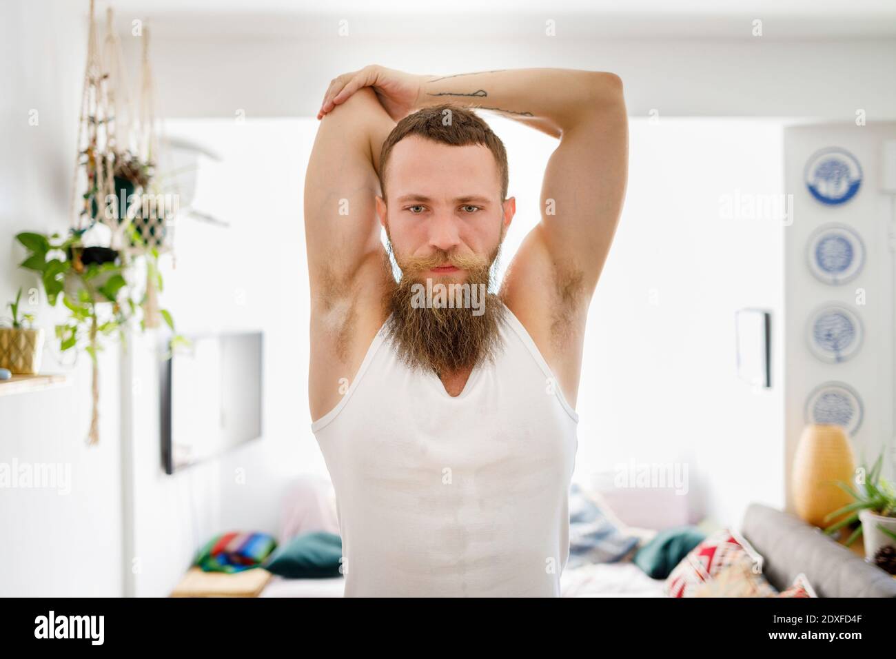 Bearded man doing stretching exercise while standing at home Stock Photo