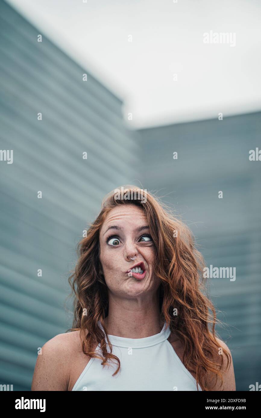 Woman with weird facial expression standing outdoors Stock Photo