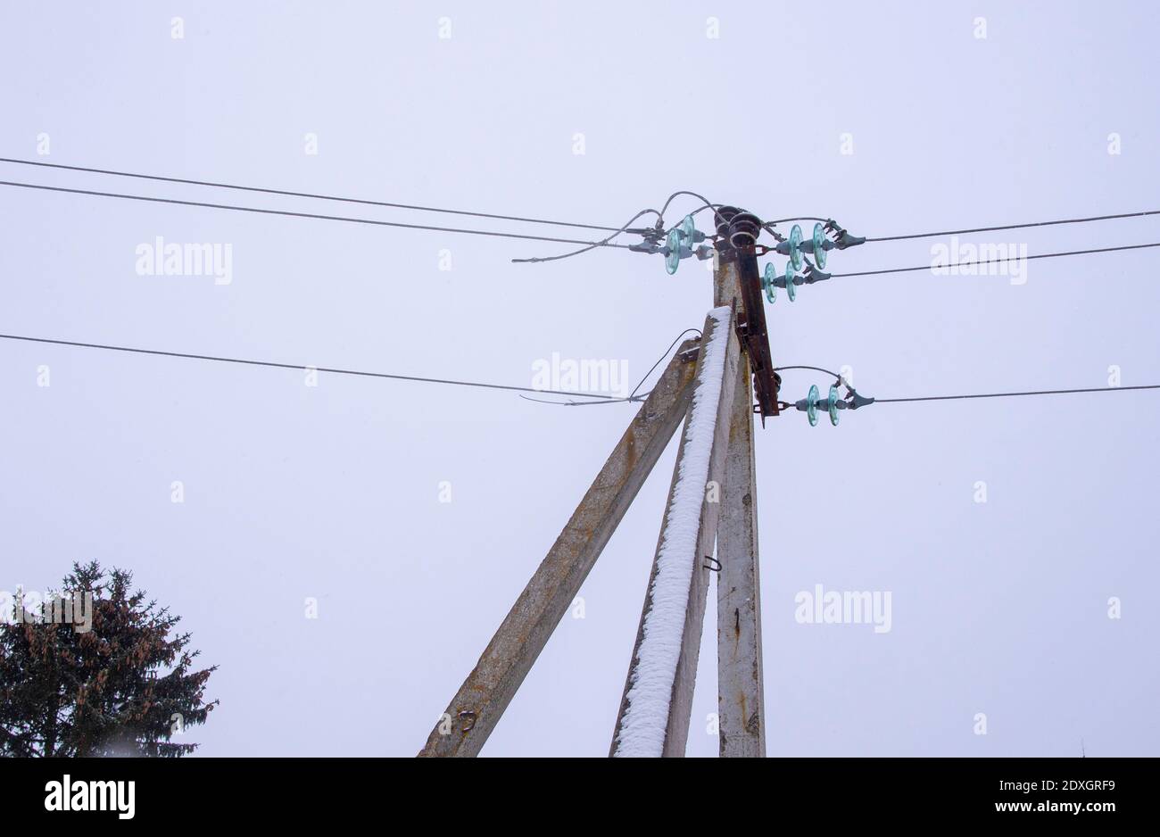 Power line sprinkled with snow against the background of a cloudy sky ...