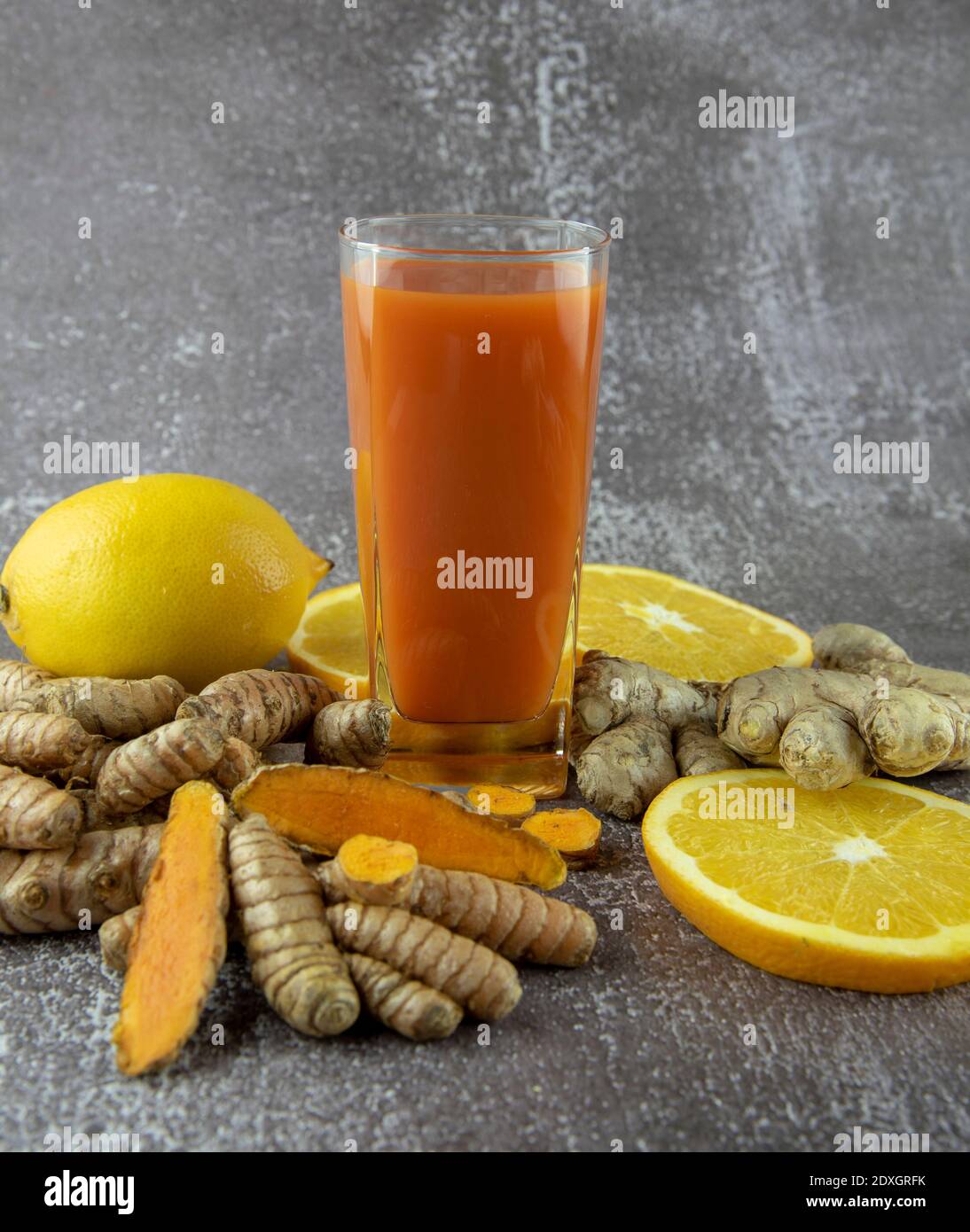 A glass of vitamin cocktail, fresh turmeric root, ginger and orange on ... A glass of vitamin cocktail, fresh turmeric root, ginger and orange on ...