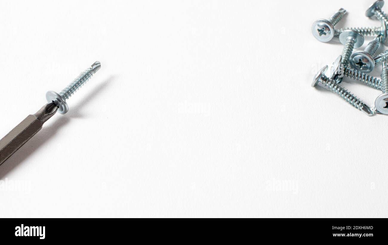 Self-cutters and screwdriver on a white background with space for text. Screw with thread - fasteners for construction, tools and accessories for repa Stock Photo