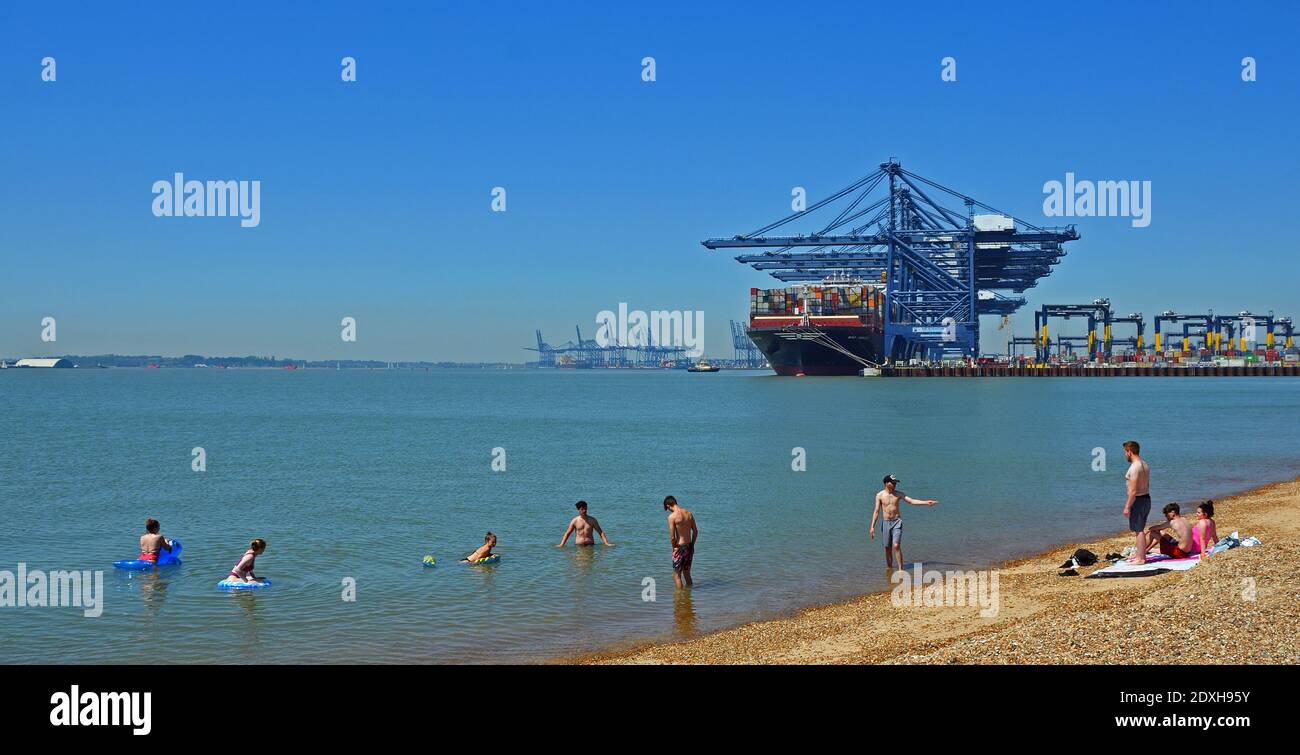 Felixstowe docks container ship being loaded with young people having a swim in the forground. Stock Photo