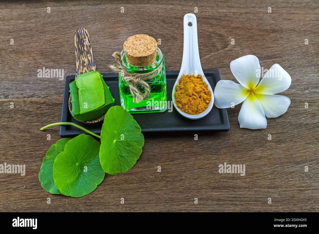 Spa herbal ( white frangipani flowers ,turmeric powder in white spoon ,Aloe vera essential oil and gel,Green Asiatic Pennywort ) on wooden background Stock Photo
