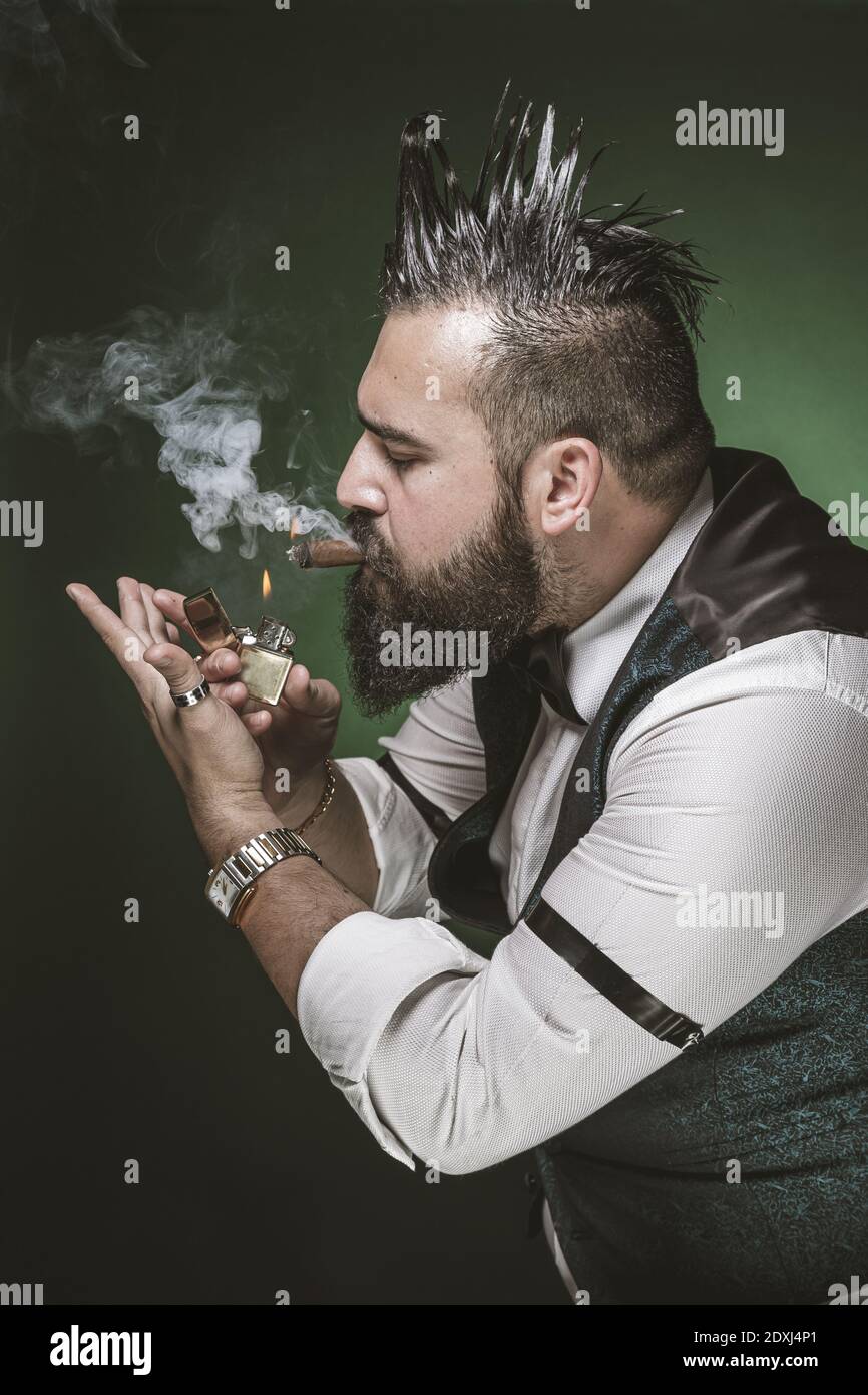 Man with a beard lighting a cigar. Stock Photo