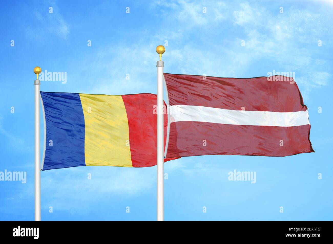 Romania and Latvia two flags on flagpoles and blue sky Stock Photo