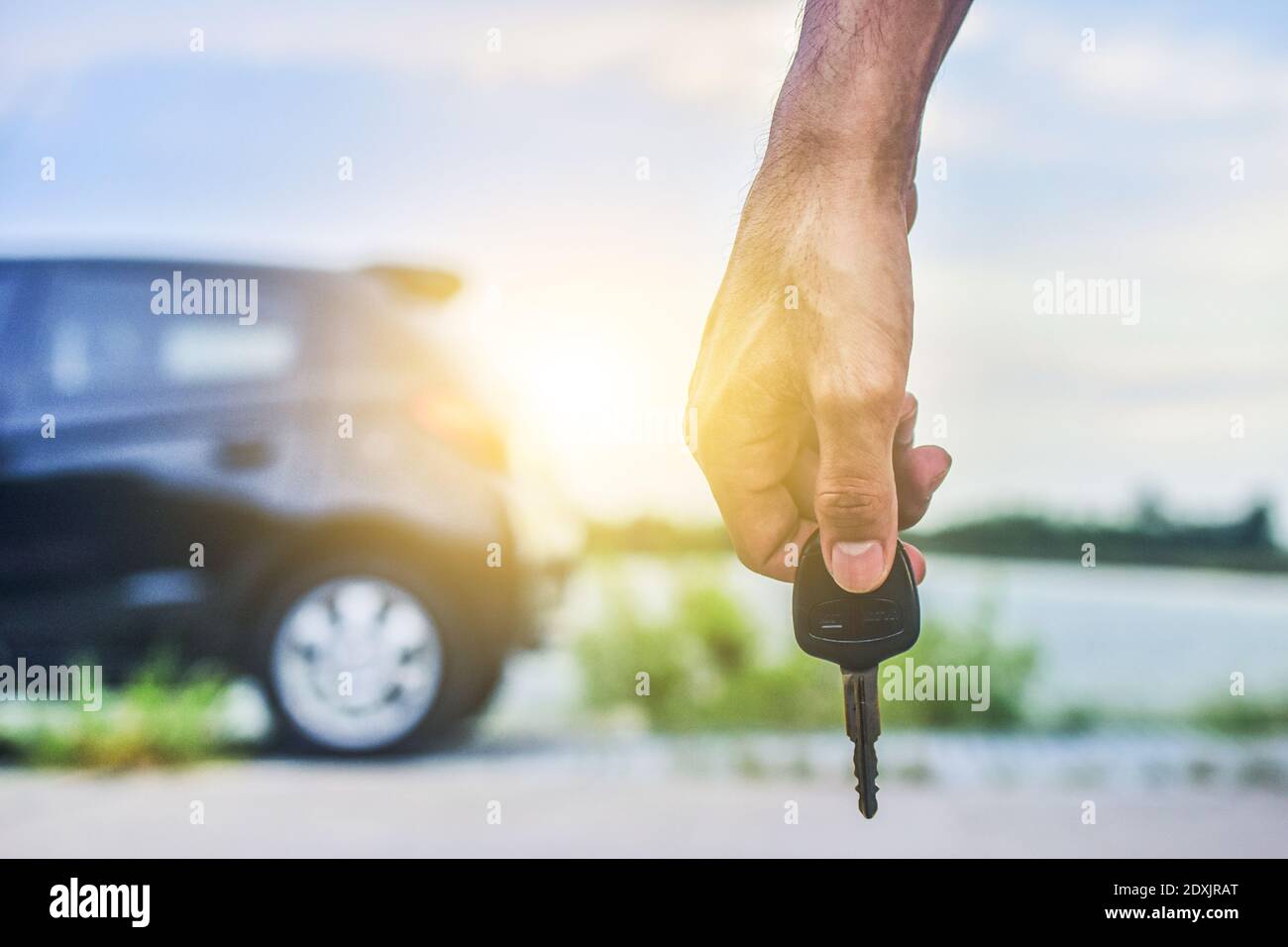 Hand holding Key and Car parked on road background Stock Photo - Alamy