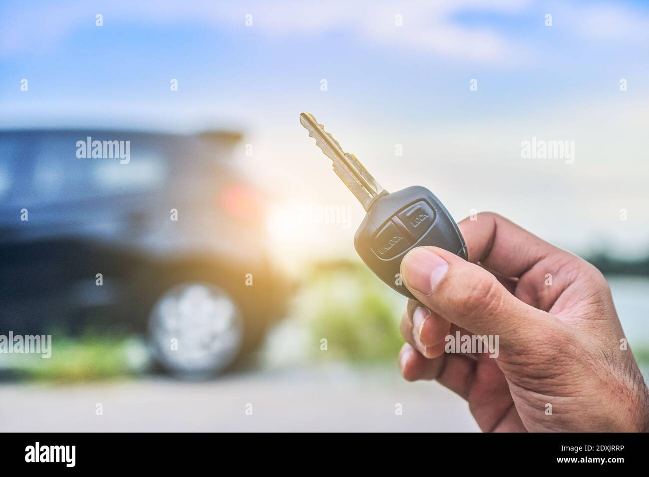Hand holding Key and Car parked on road background Stock Photo - Alamy