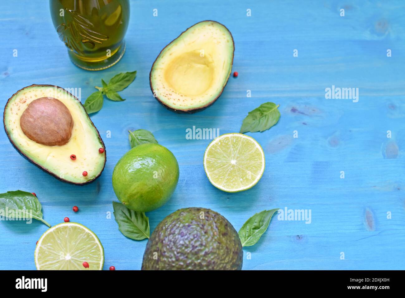 Top table concept with avocado, olive oil, limes and mint leaves on blue background. Copy text space Stock Photo