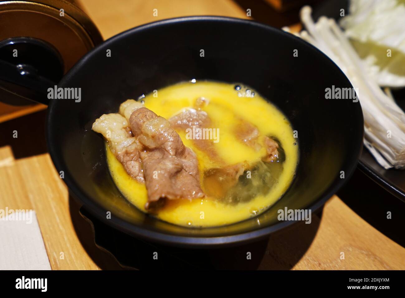 Wooden table fulled of vegetables, Sliced Wagyu beef and pork, raw egg