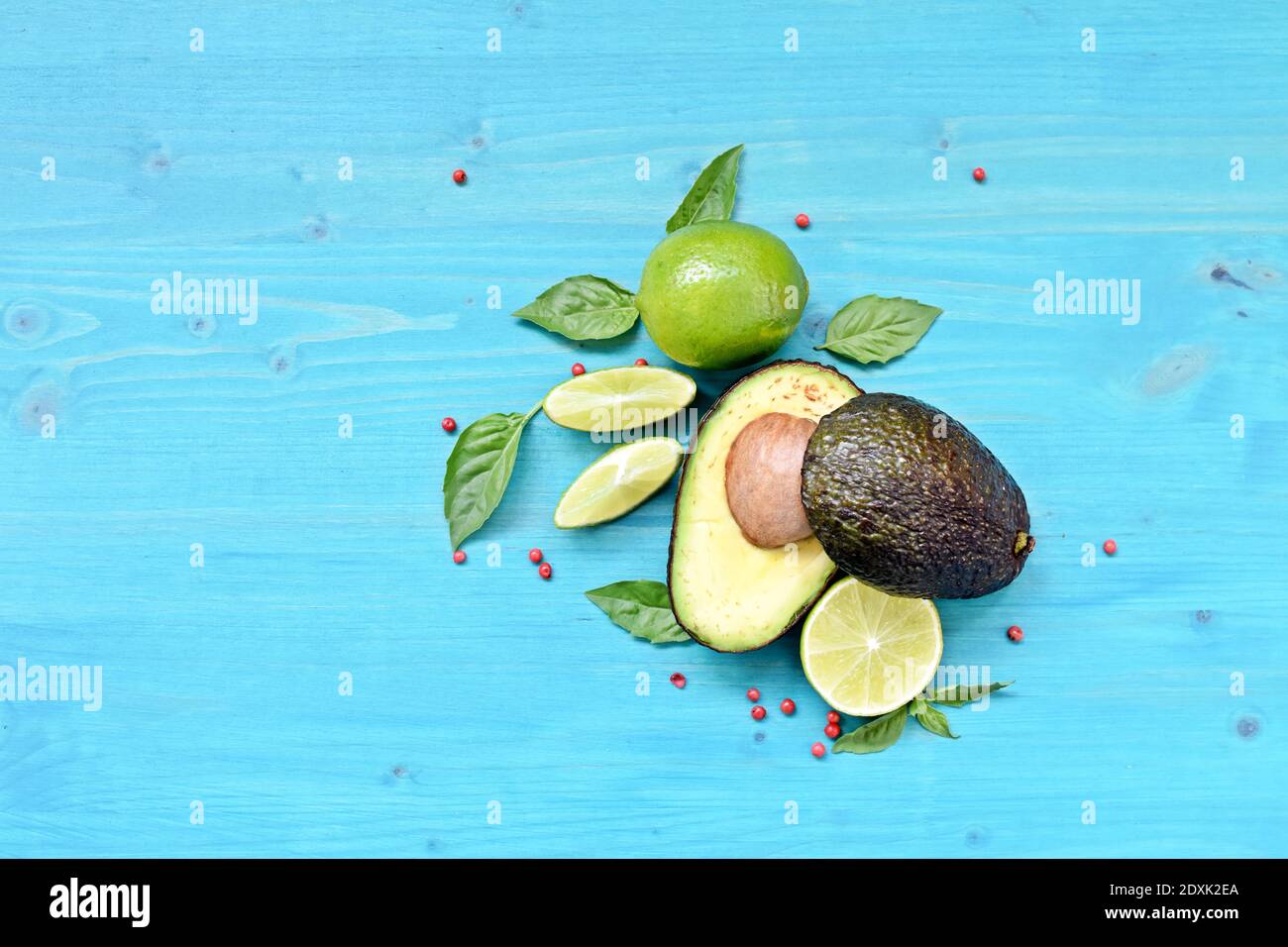 Top dish with raw food. Avocado, limes, lemons and mint on blue background. Copy space text. Stock Photo