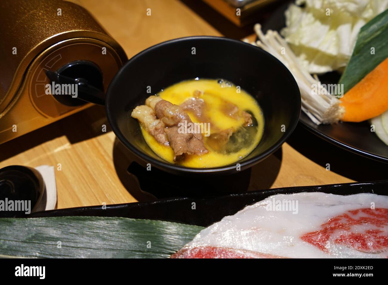Wooden table fulled of vegetables, Sliced Wagyu beef and pork, raw egg