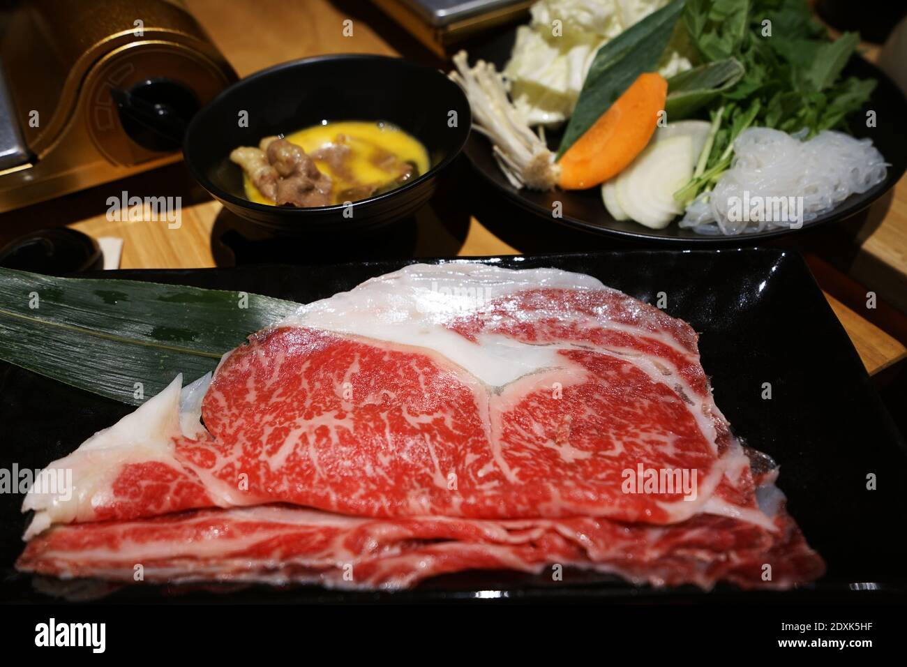 Wooden table fulled of vegetables, Sliced Wagyu beef and pork, raw egg