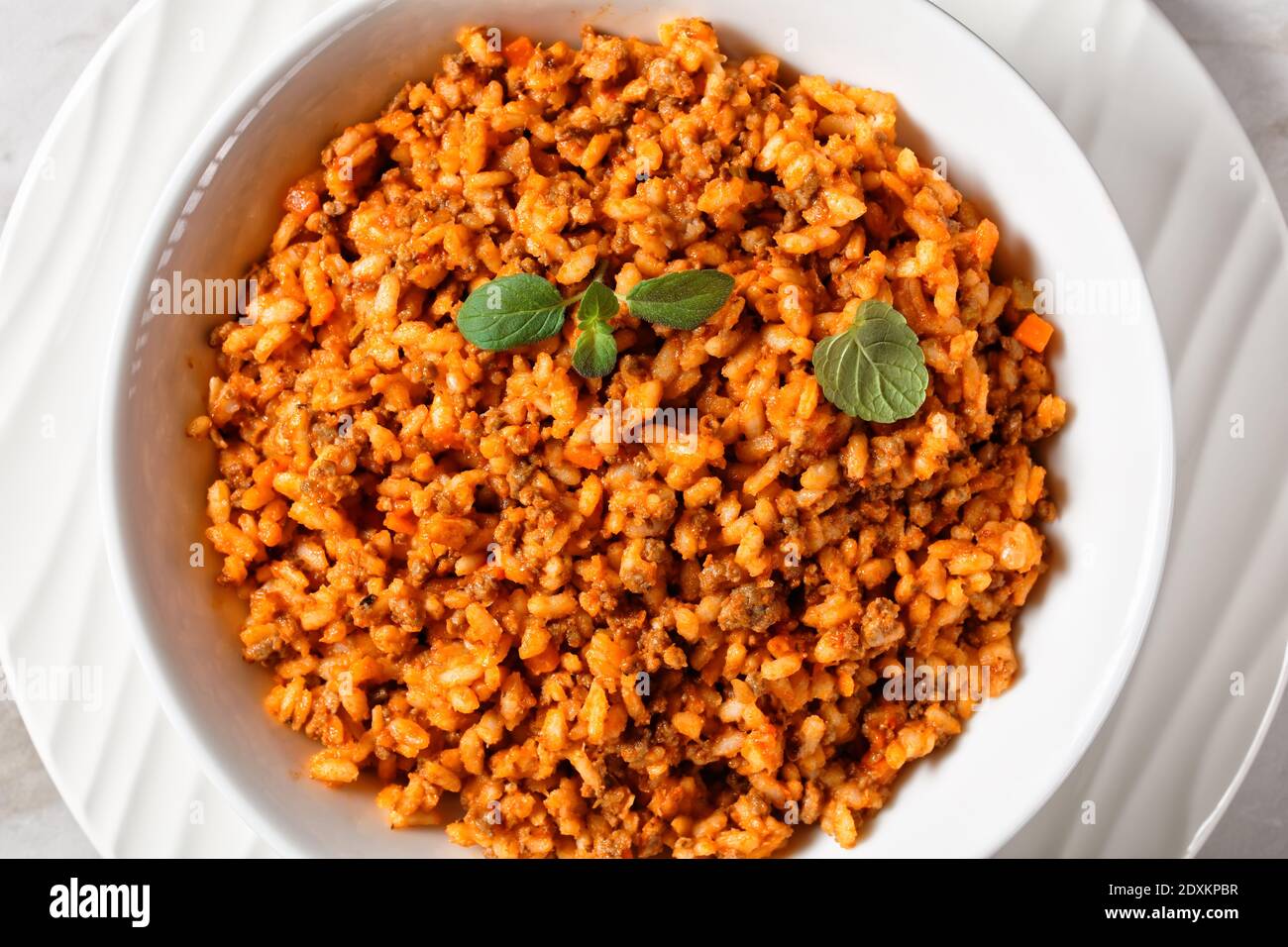 ground beef risotto bolognese in a white bowl on a marble table
