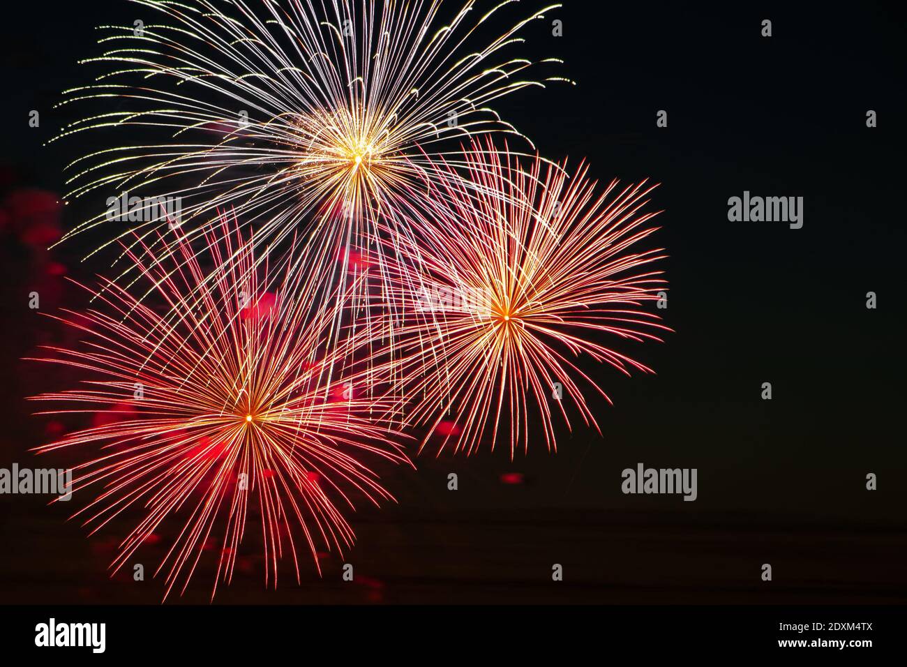 Beautiful festive fireworks in the sky for a holiday. Bright multi-colored salute on a black background. Place for text. Stock Photo