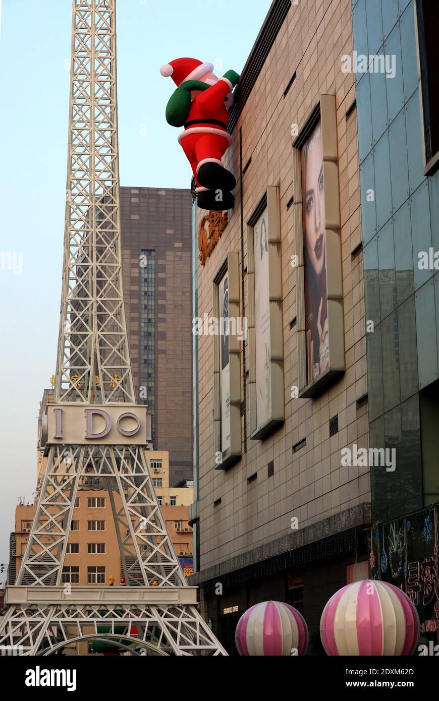 An enormous Santa Claus sculpture is seen climbing on the wall of a local mall in Huai¯an city, east China¯s Jiangsu province, 24 December 2020. *** L Stock Photo