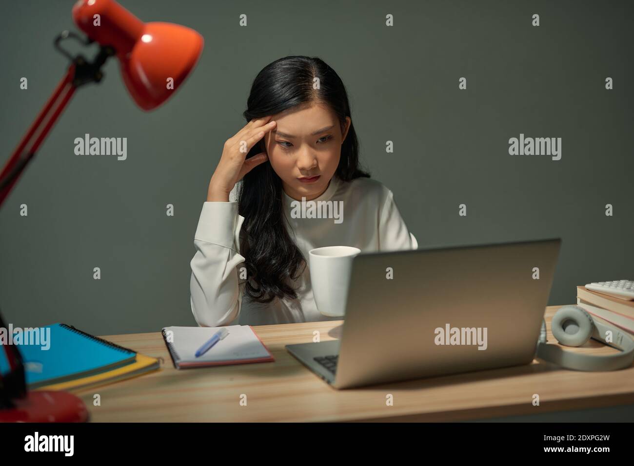 young woman drinking coffee and reading something on computer screen Stock Photo