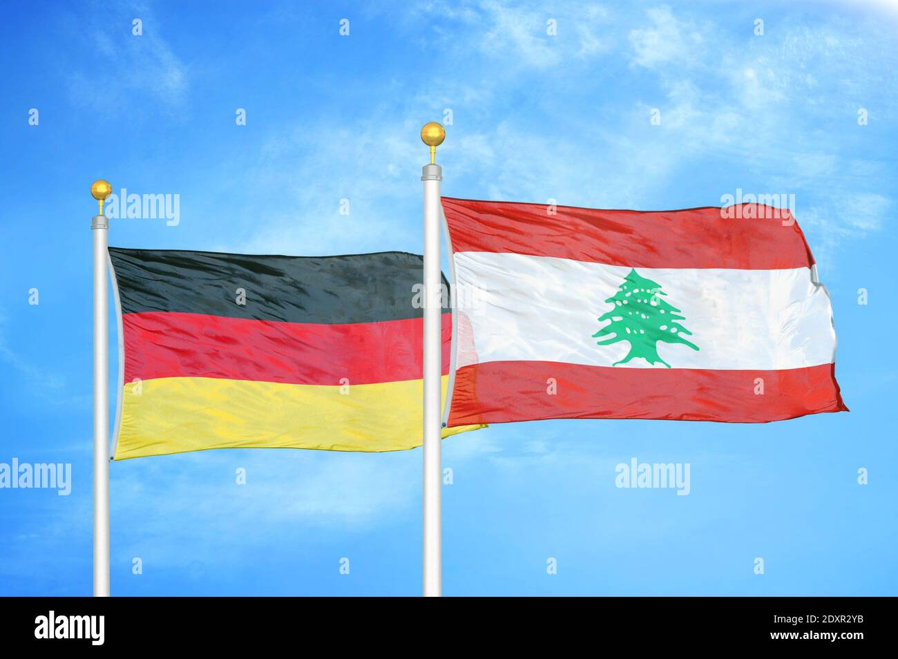 Germany and Lebanon two flags on flagpoles and blue cloudy sky Stock Photo