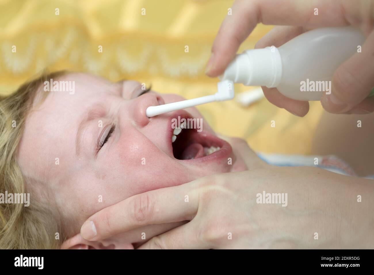 Boy Inhaling Nasal Spray on bed at home Stock Photo