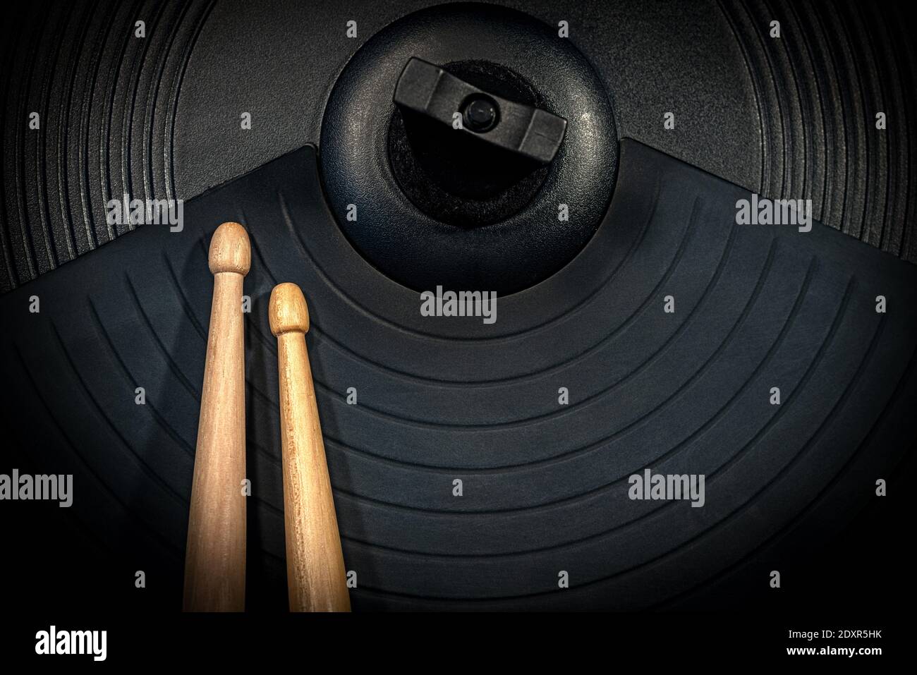 Extreme closeup of two wooden drumsticks on a black cymbal of an