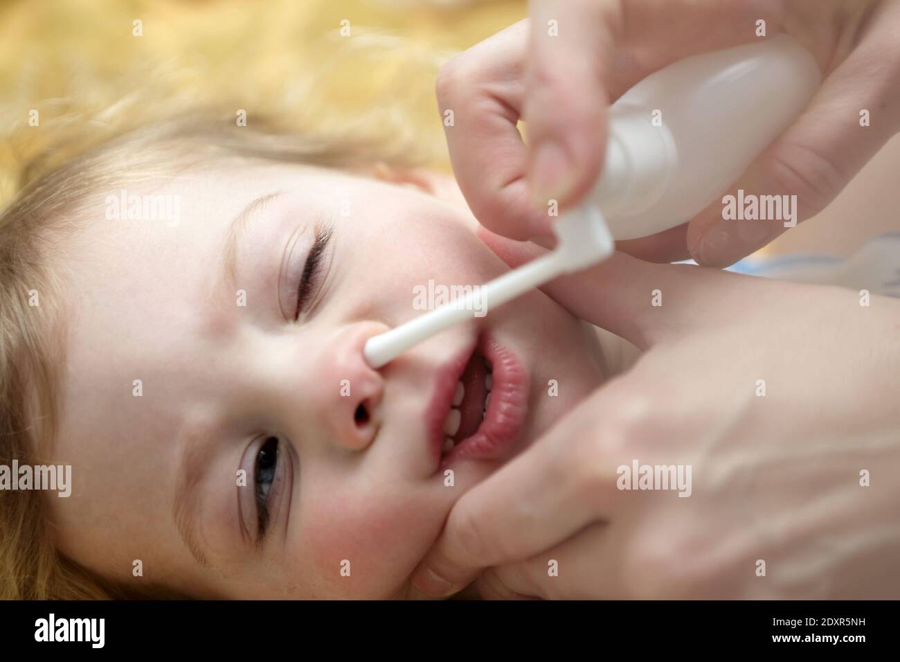 Child Inhaling Nasal Spray on bed at home Stock Photo