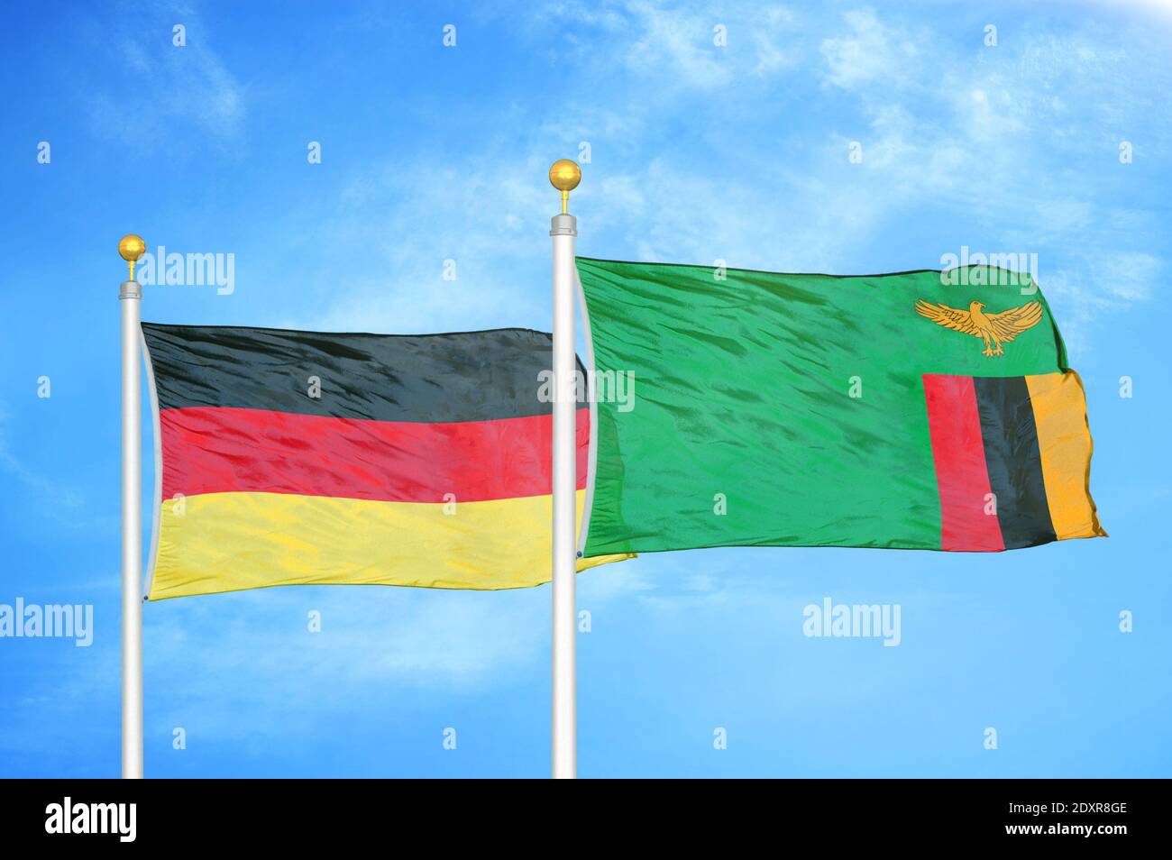Germany and Zambia two flags on flagpoles and blue cloudy sky Stock Photo