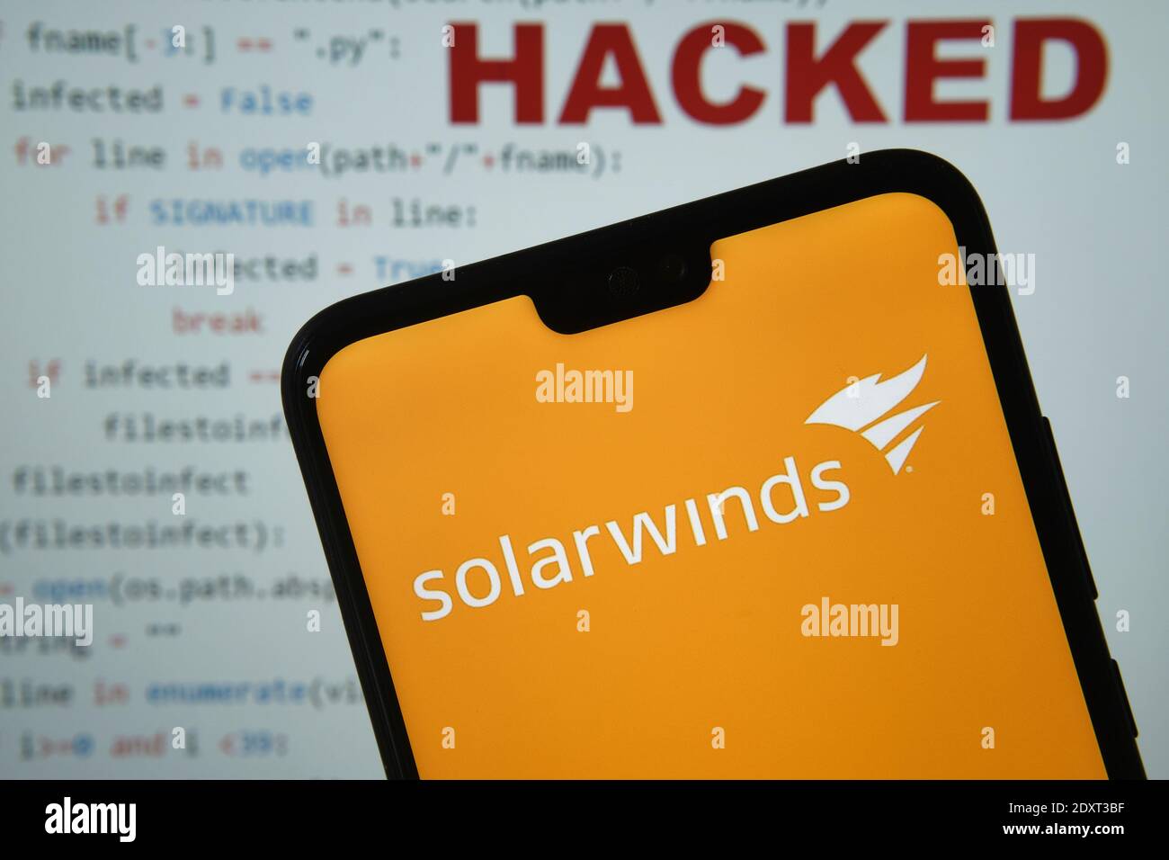 Stafford, United Kingdom - December 24 2020: Solarwinds logo seen on the smartphone screen, with simple brute force attack code with HACKED word on th Stock Photo