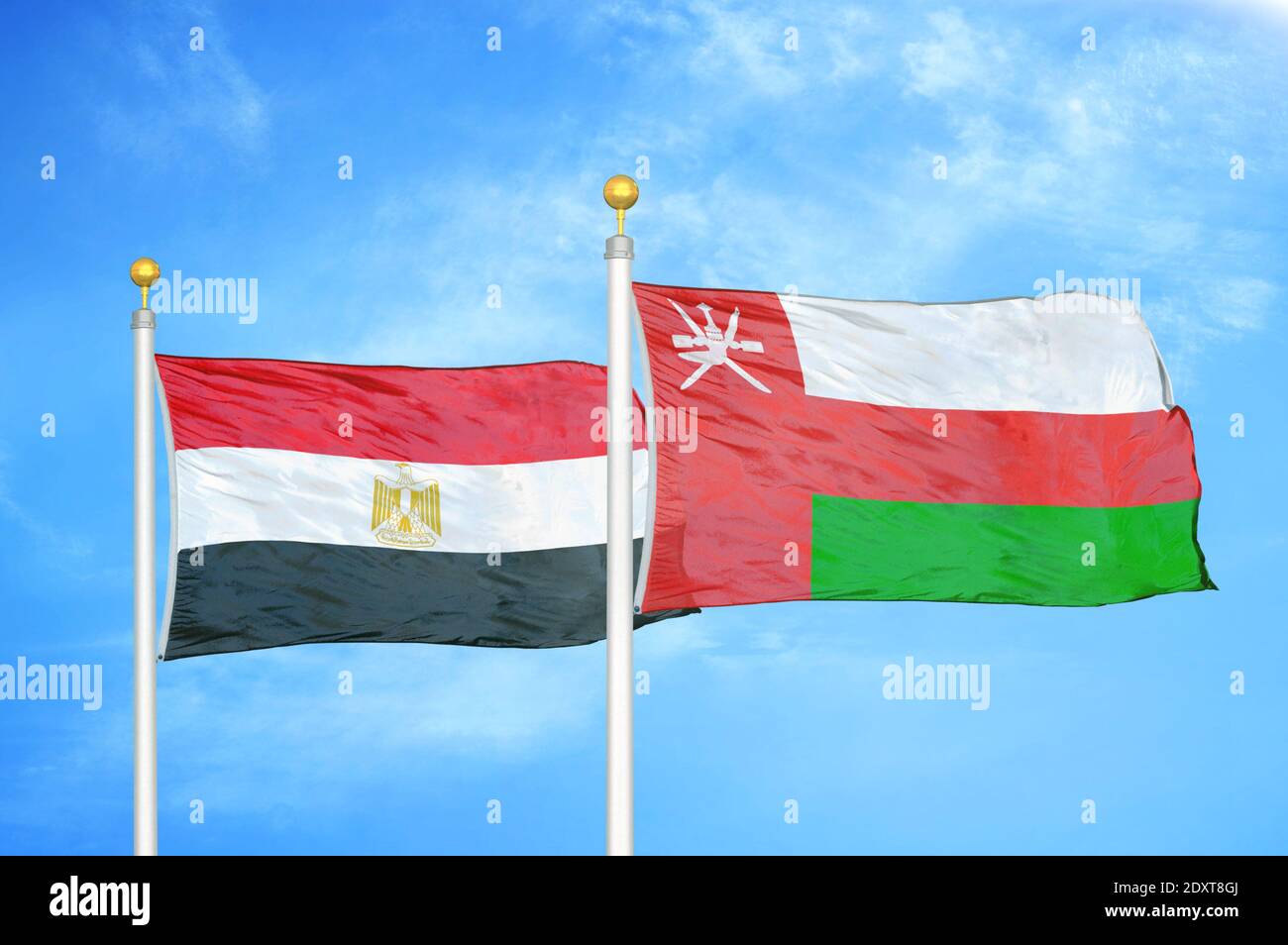 Egypt and Oman two flags on flagpoles and blue cloudy sky Stock Photo