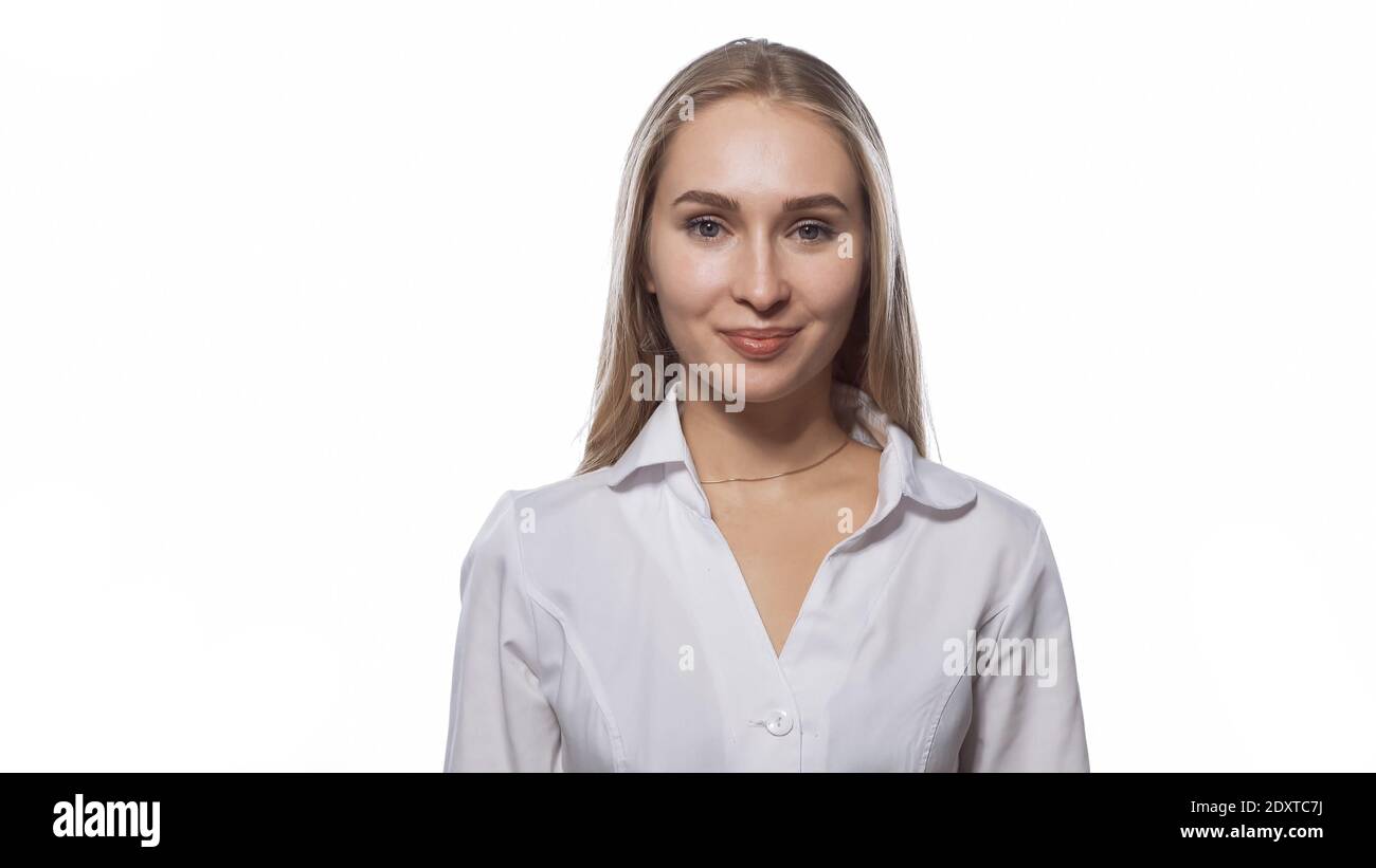 Beautiful young woman with long straight blond hair looking at the camera wearing white medical uniform isolated on white background Stock Photo