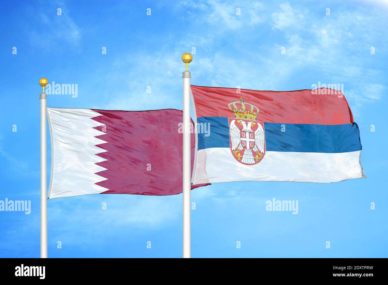 Qatar and Serbia two flags on flagpoles and blue cloudy sky Stock Photo