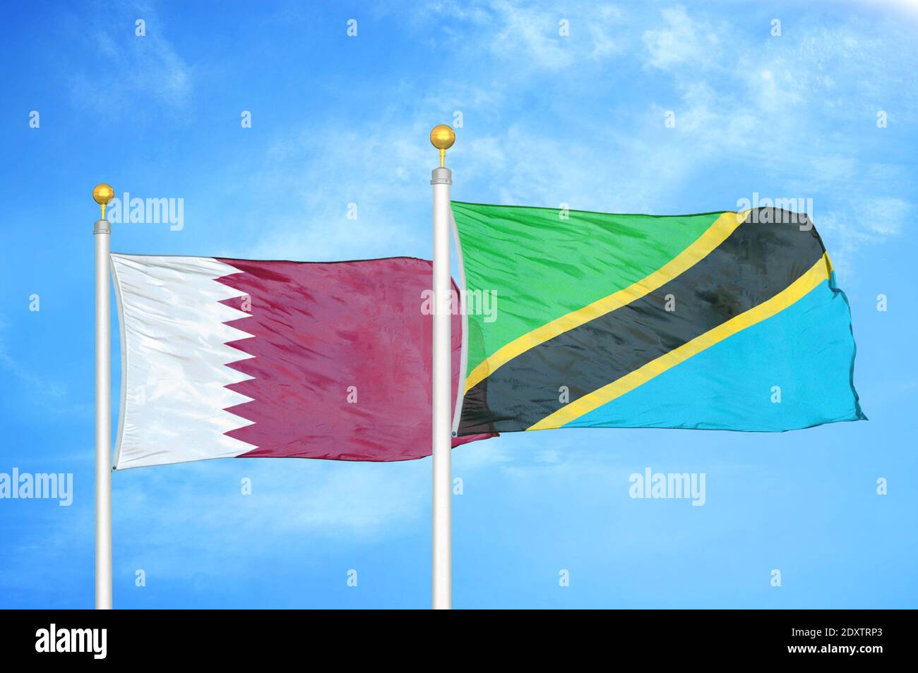 Qatar and Tanzania two flags on flagpoles and blue cloudy sky Stock ...