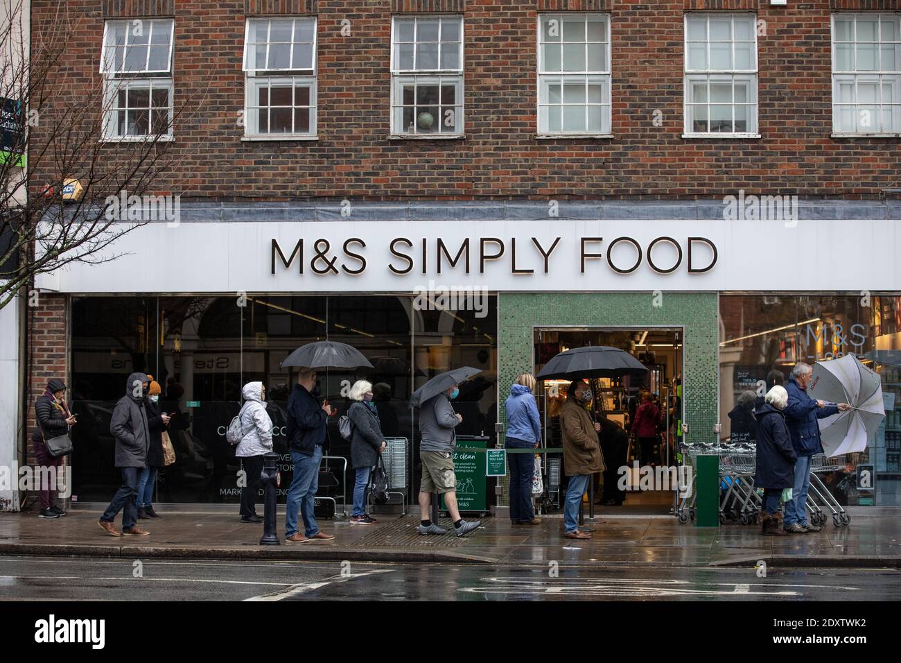 Queues of shoppers lining up to collect their Christmas supplies outside a Marks & Spencers Simply Food in Twickenham, Richmond, England, UK Stock Photo