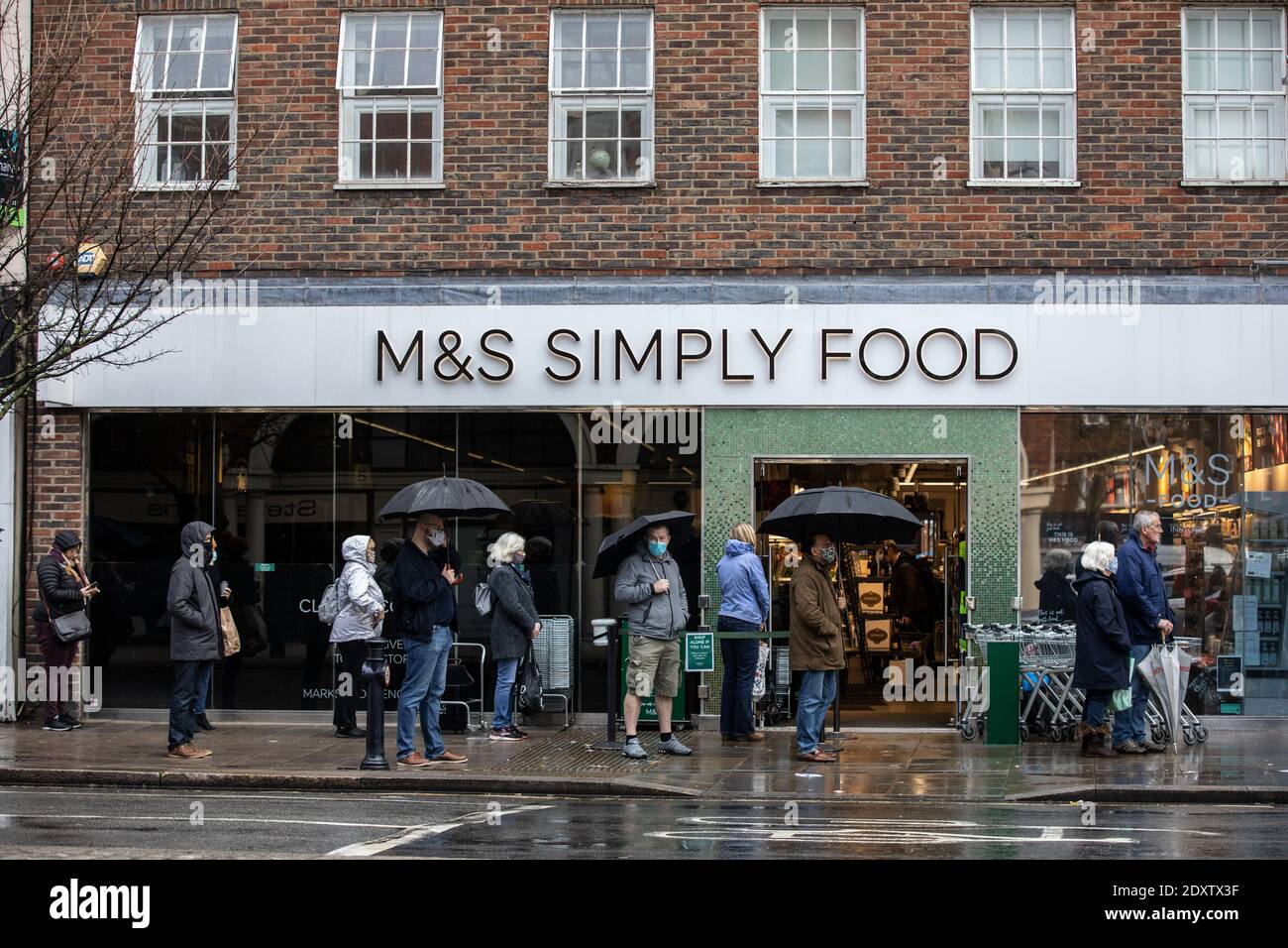 Queues of shoppers lining up to collect their Christmas supplies outside a Marks & Spencers Simply Food in Twickenham, Richmond, England, UK Stock Photo