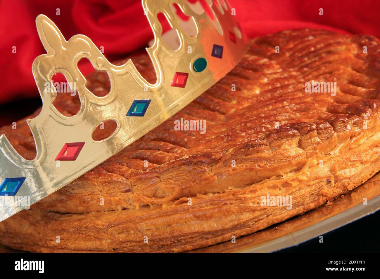Traditional galette des rois or French king's cake with golden paper crown placed on it - Stock Image