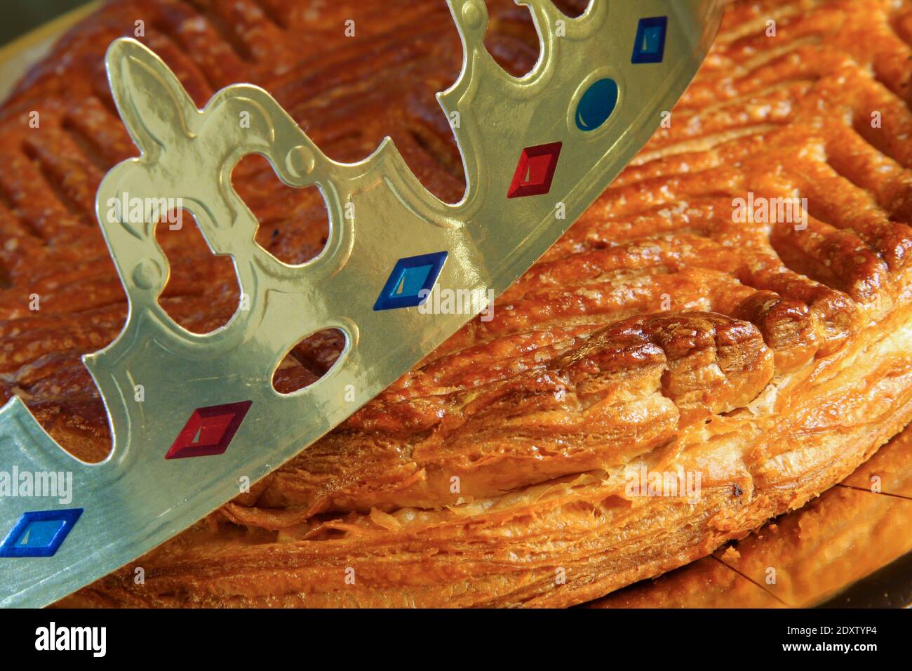 Traditional galette des rois or French king's cake with golden paper crown placed on it - Stock Image